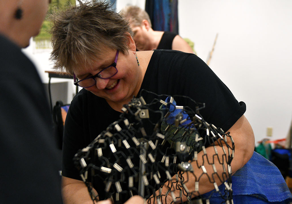 Debbie Prost adjusts a mannequin during setup for the Columbia Weavers and Spinners' Guild's 30th Annual Holiday Exhibition and Sale